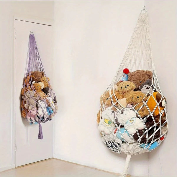 A macrame hammock filled with various stuffed animals hanging on a white wall.