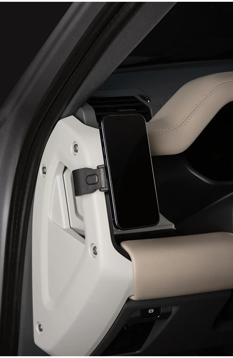 A white magnetic car phone mount is shown inside a vehicle, holding a smartphone.