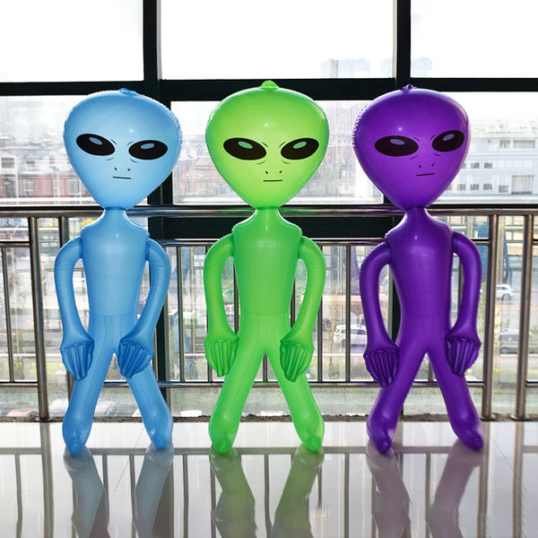 Three inflatable alien decorations in blue, green, and purple standing on a reflective floor.