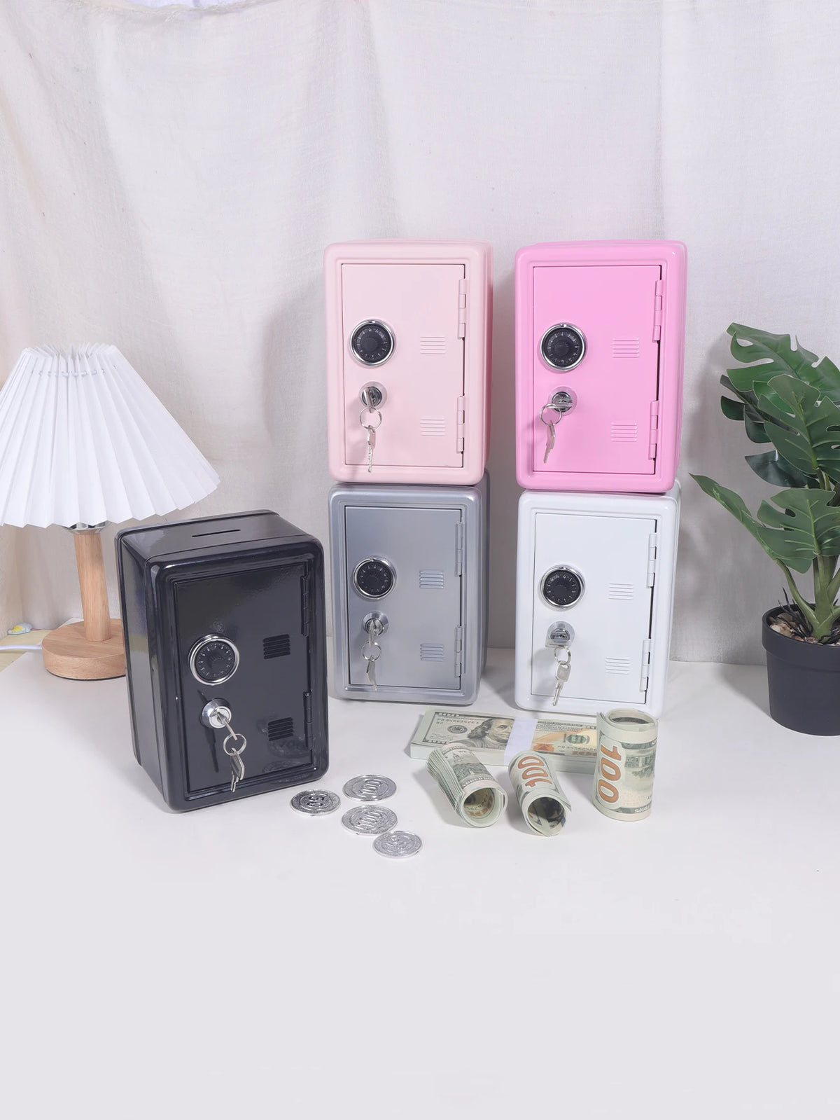 A collection of solid color metal piggy banks in pink, gray, and white, along with coins and cash.