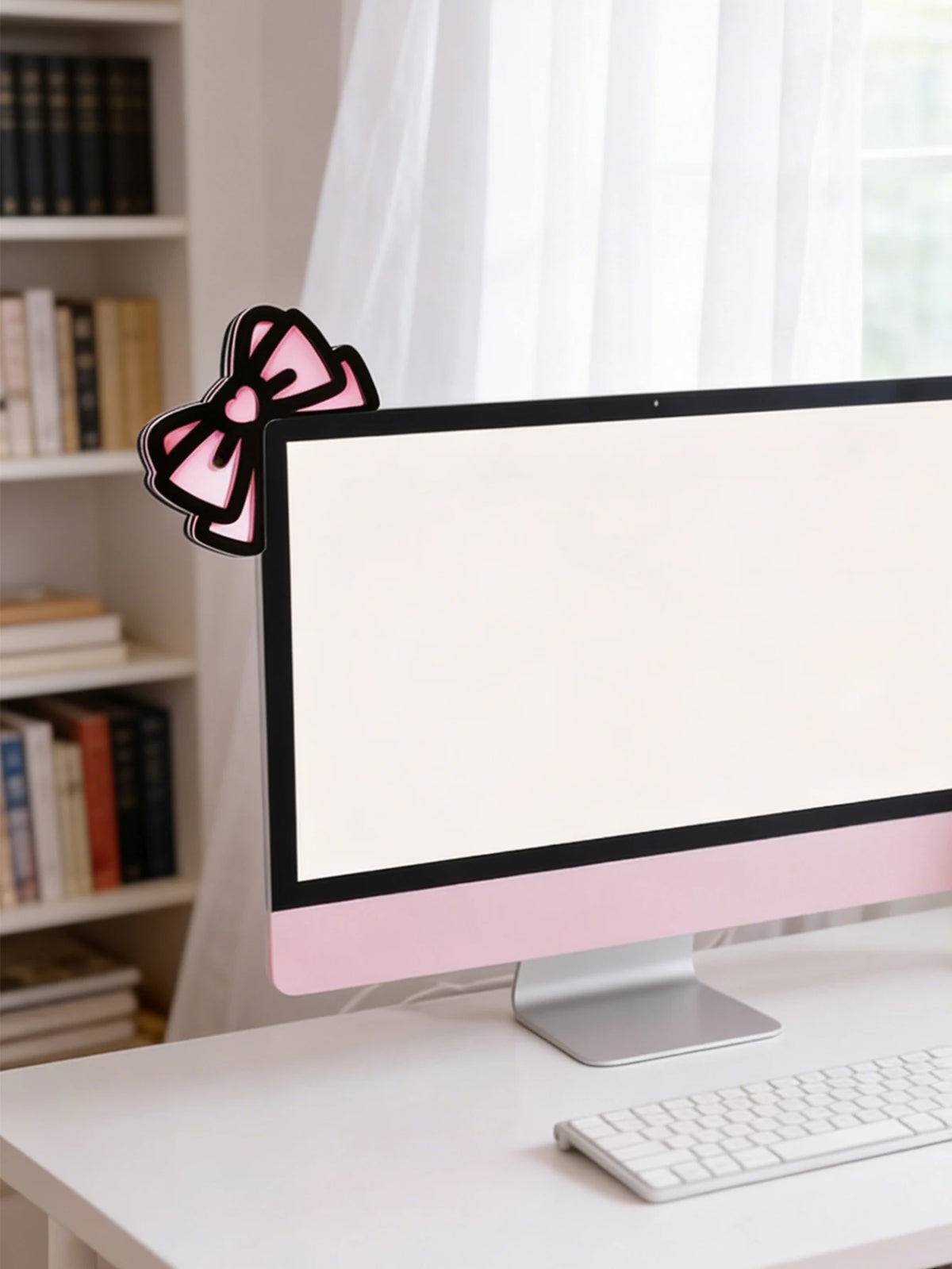 Un écouteur d'oreille de chat en nœud rose décoratif repose sur un bureau blanc devant un écran d'ordinateur.