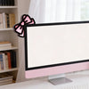 Un oreillette d'oreille de chat en nœud rose décoratif est posé sur un bureau blanc devant un écran d'ordinateur.