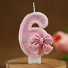 Pink glitter number six candle with a pink bow on a white stick