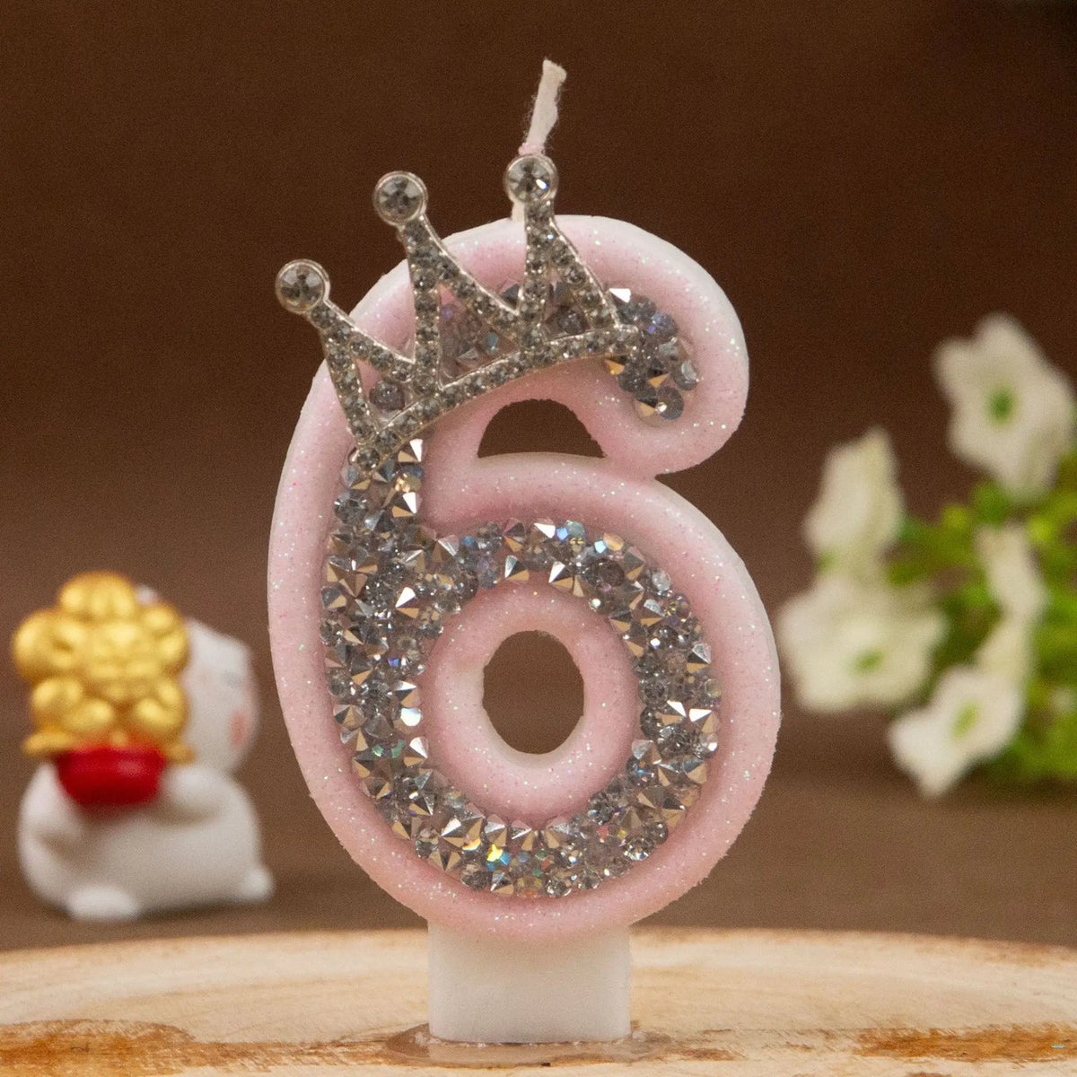 Rosa Geburtstagskerze in Form der Ziffer 6 mit Diamantkrone und kleiner weißer Figur