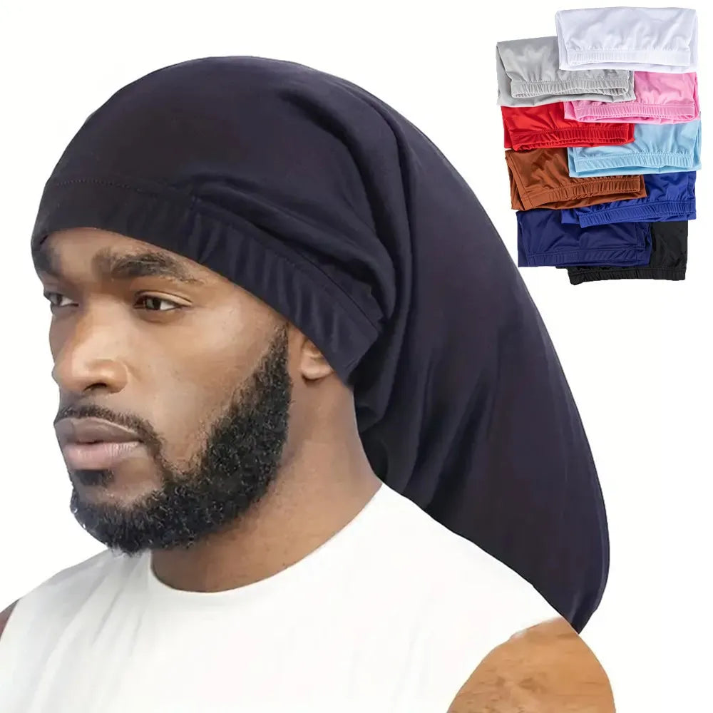 A man wearing a dark blue satin hair bonnet with various colored fabric options displayed nearby.