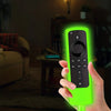 Una mano sostiene una cubierta de silicona verde brillante para un dispositivo Fire Stick en una sala de estar con poca luz.