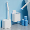 A white heavy-duty disposable toilet brush kit with a long handle is mounted on a wall next to a toilet.