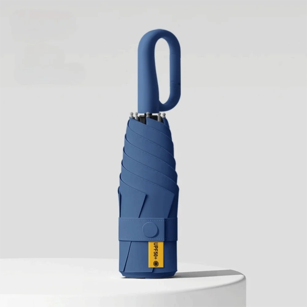A blue compact folding umbrella with a handle and protective sleeve is shown against a light gray background.