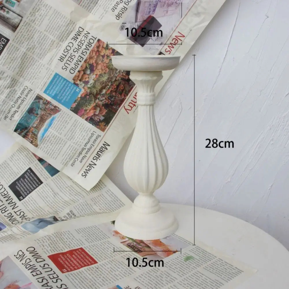 White antique wood decorative candlestick holders on a white surface with measurement lines.