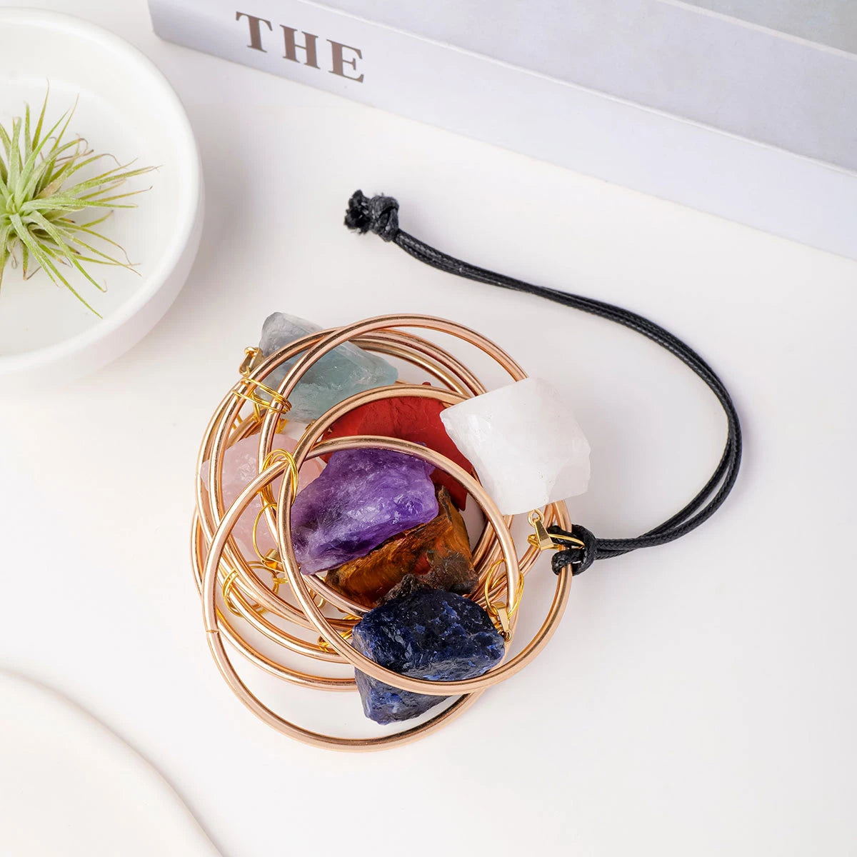 A set of seven crystals in gold wire rings suspended on a black leather cord.
