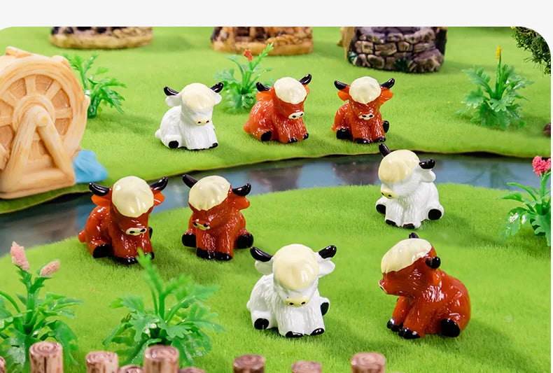 A collection of resin highland cow figurines in white and orange colors displayed on a green textured surface.