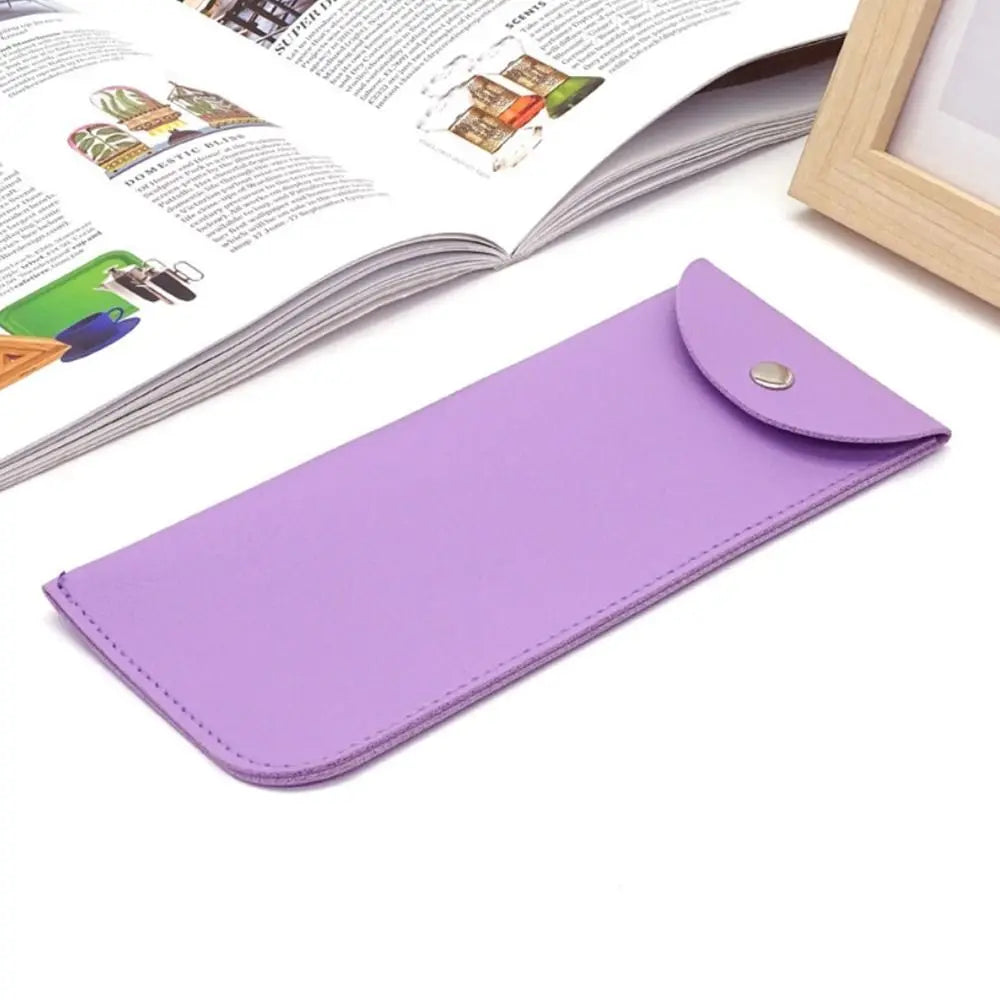 A purple PU leather eyewear case or glasses bag lying next to an open book.