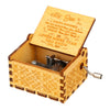 A vintage engraved wooden music box with a lid open showing an inscription on the inside
