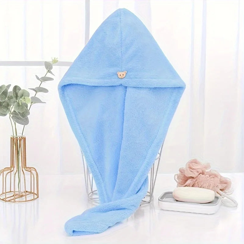 Light blue microfiber hair drying wrap towel with a small bear charm displayed on a clear stand.