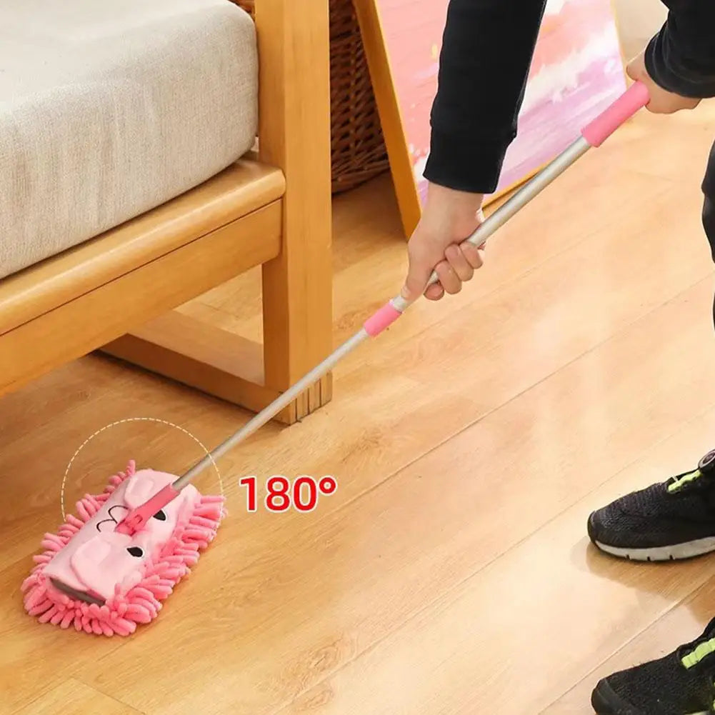 A pink toddler mini broom and dustpan set with a long handle is shown on a wooden floor.