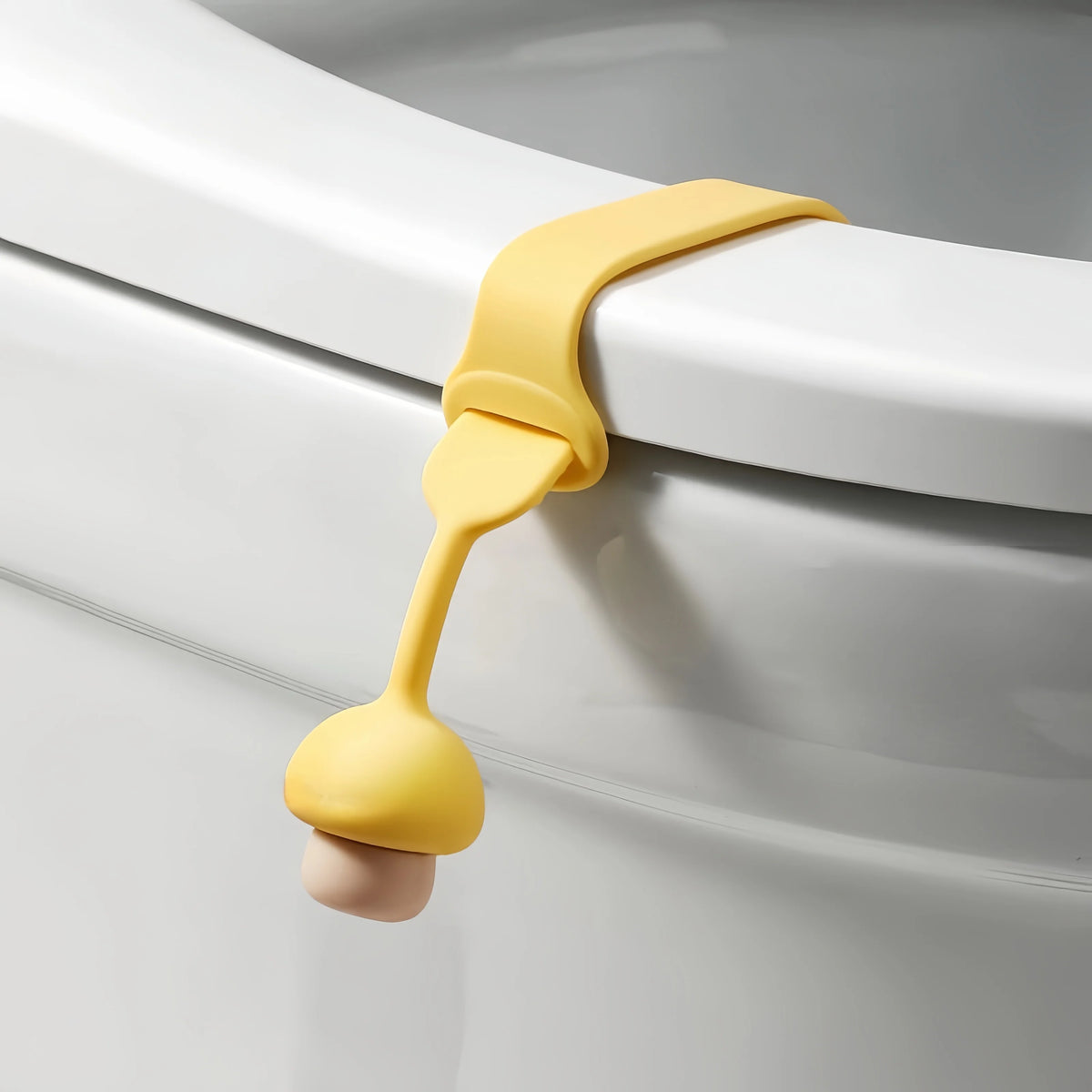 A yellow silicone toilet seat lifter ring opener is shown against a white porcelain toilet bowl.