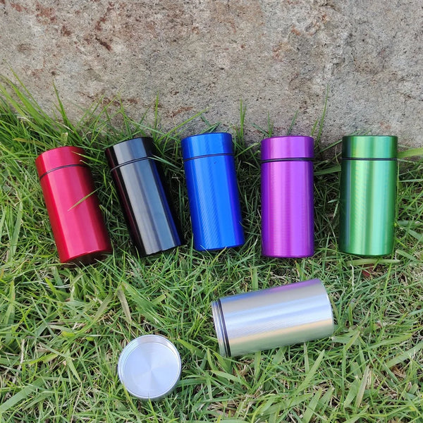 A collection of colorful airtight aluminum stash jars arranged on green grass.
