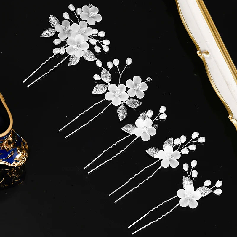 A set of silver pearl flower bridal hair clips displayed against a black background.