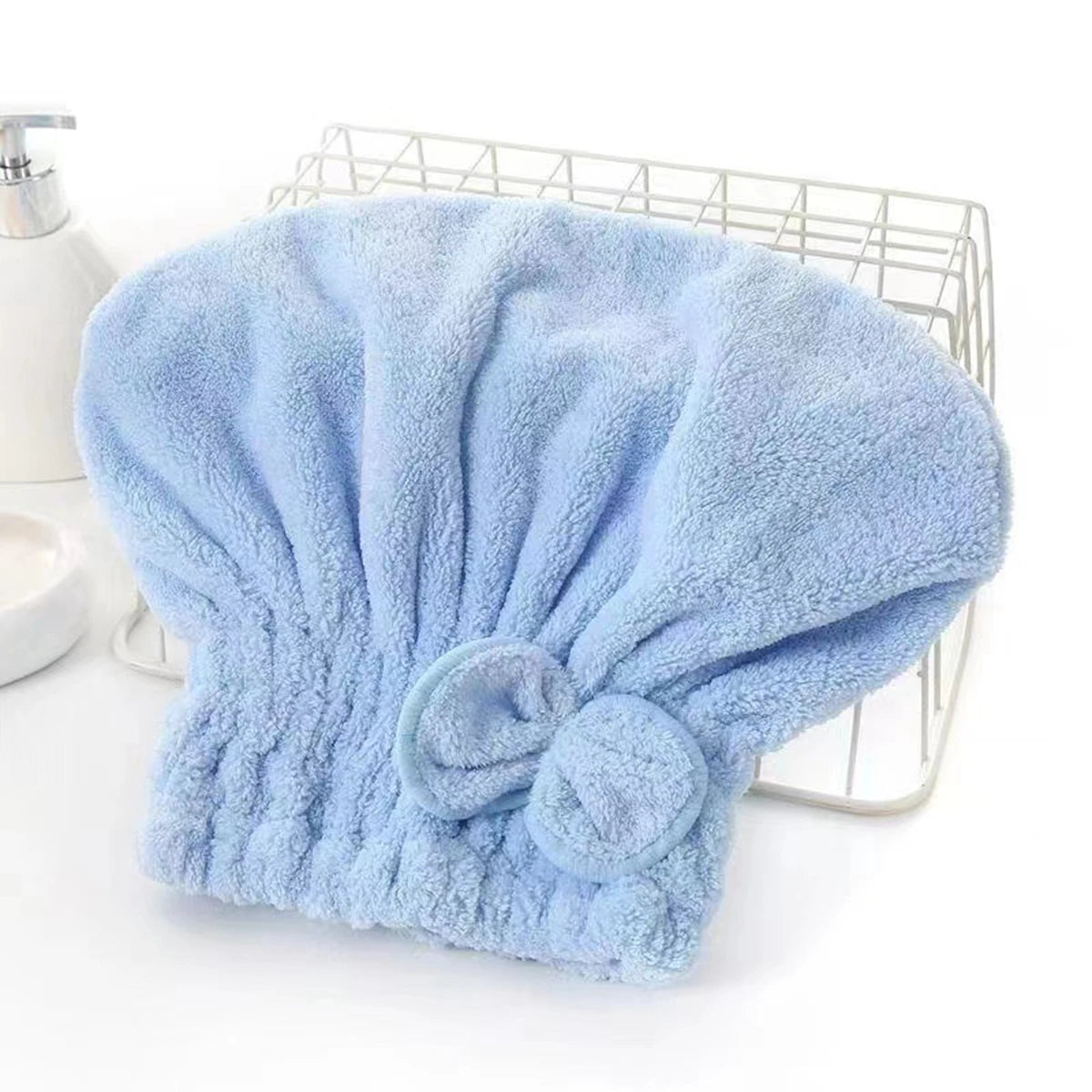 A light blue microfiber hair drying cap and towel with a fluffy texture resting on a wire rack.