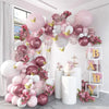 A pink and white balloon floral arrangement decorated with butterfly stickers on a white wall.