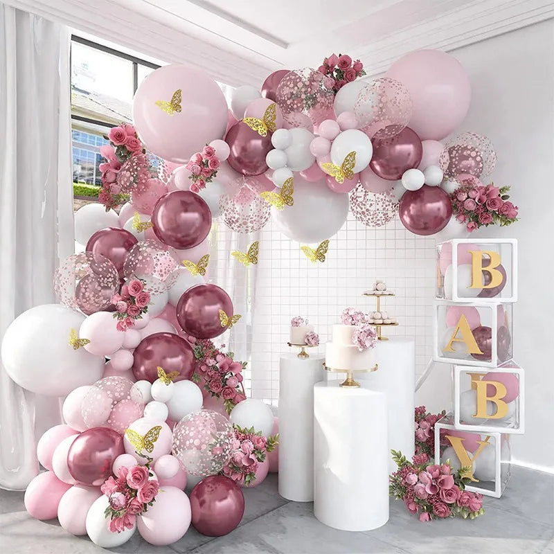 A pink and white balloon floral arrangement decorated with butterfly stickers on a white wall.