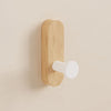 A light wood wall hook with a white, round mounting piece attached to a beige wall.
