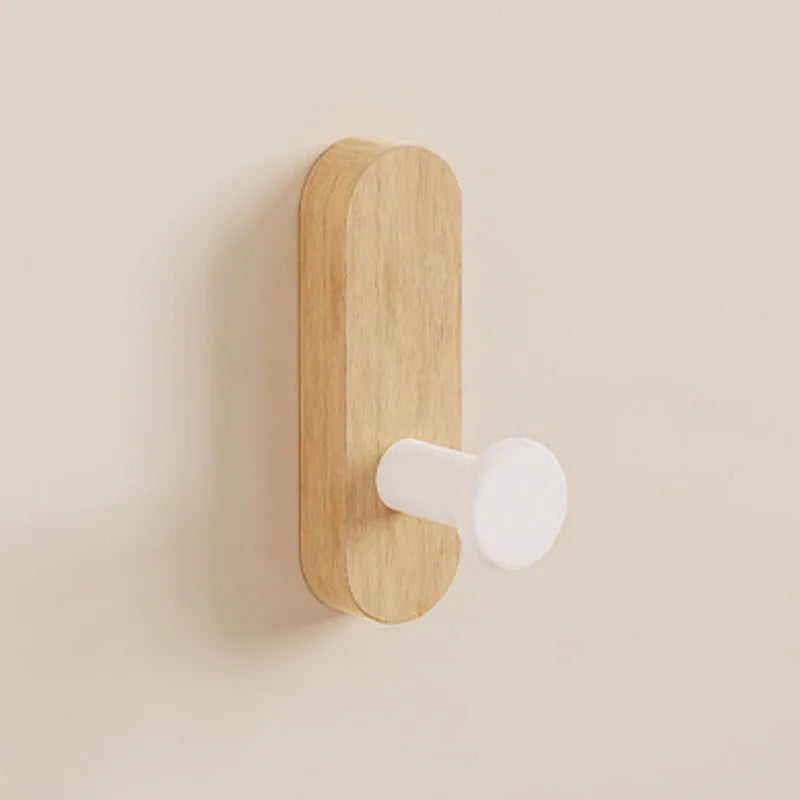 A light wood wall hook with a white, round mounting piece attached to a beige wall.
