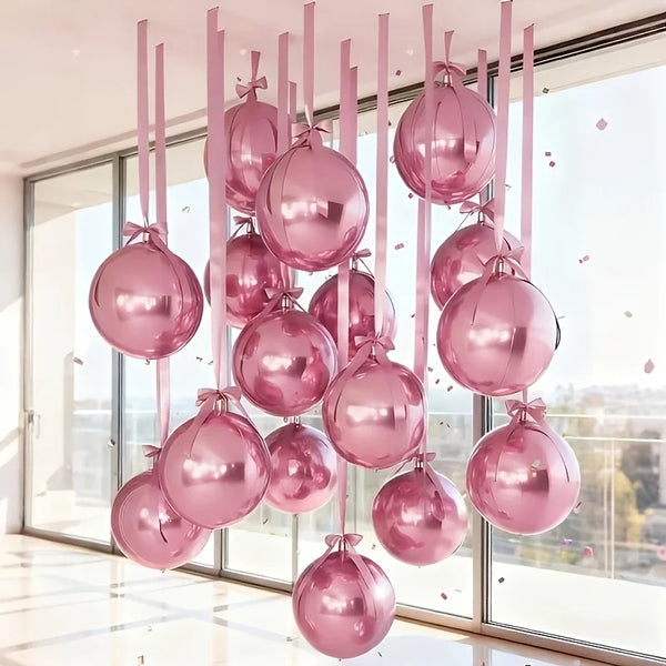A vertical arrangement of ten pink metallic foil balloons hanging in front of a large window.