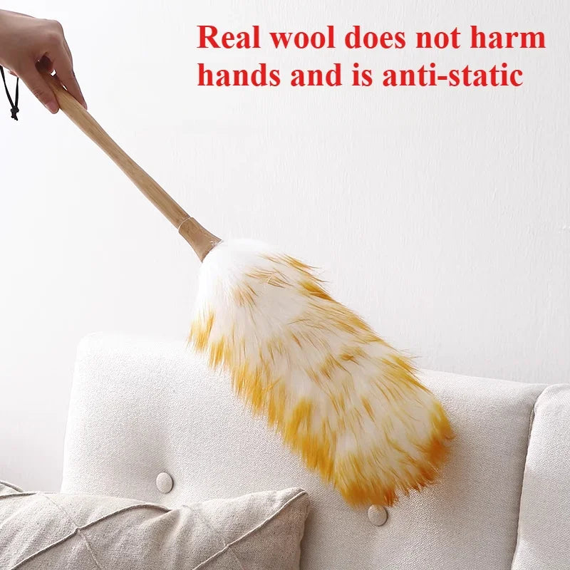 A hand is holding a yellow and white fluffy broom made of real wool, emphasizing that it does not harm hands and is anti-stat