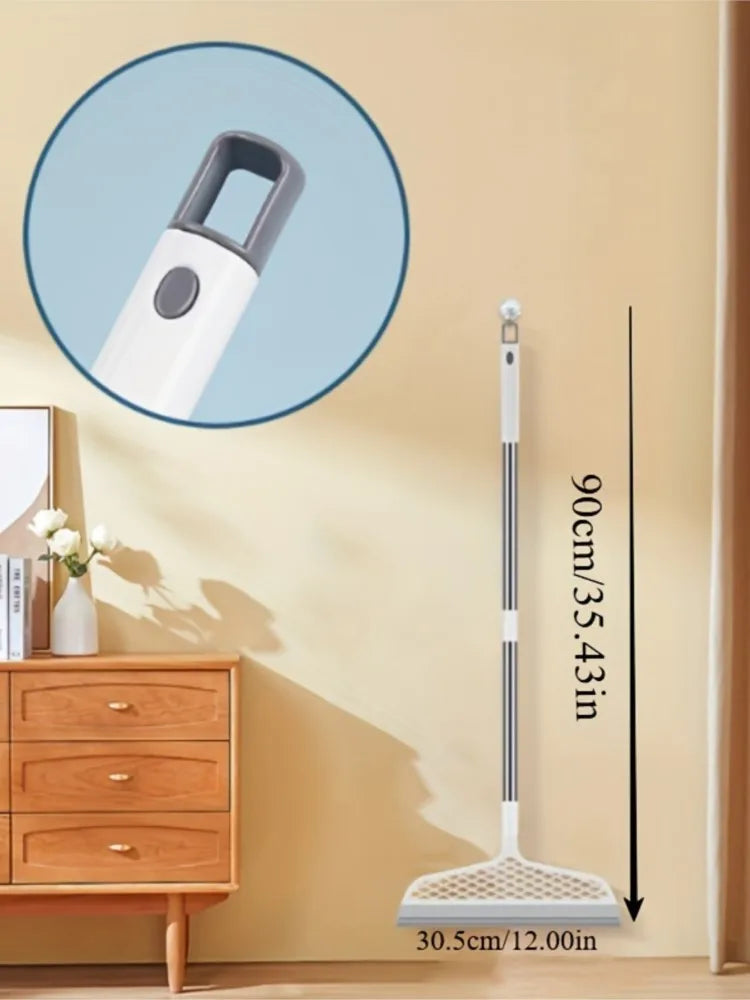 A long, white ergonomic broom and scraper set with a flexible handle and wide cleaning head is shown against a light wall.