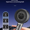 A hand holds a silver shower head with multiple buttons and a switch key over a piano keyboard.
