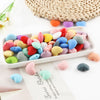 A collection of 10 colorful silicone heart charm beads in various shades of pink, yellow, blue, and red arranged on a white t