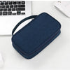 A dark blue multi-purpose travel electronics organizer bag resting on a white surface next to a laptop and mouse.