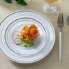 Weißer Dinner-Teller mit silbernen Ringen, der eine Portion orangefarbenen Lachs mit Radieschenscheiben und grünen Punkten en