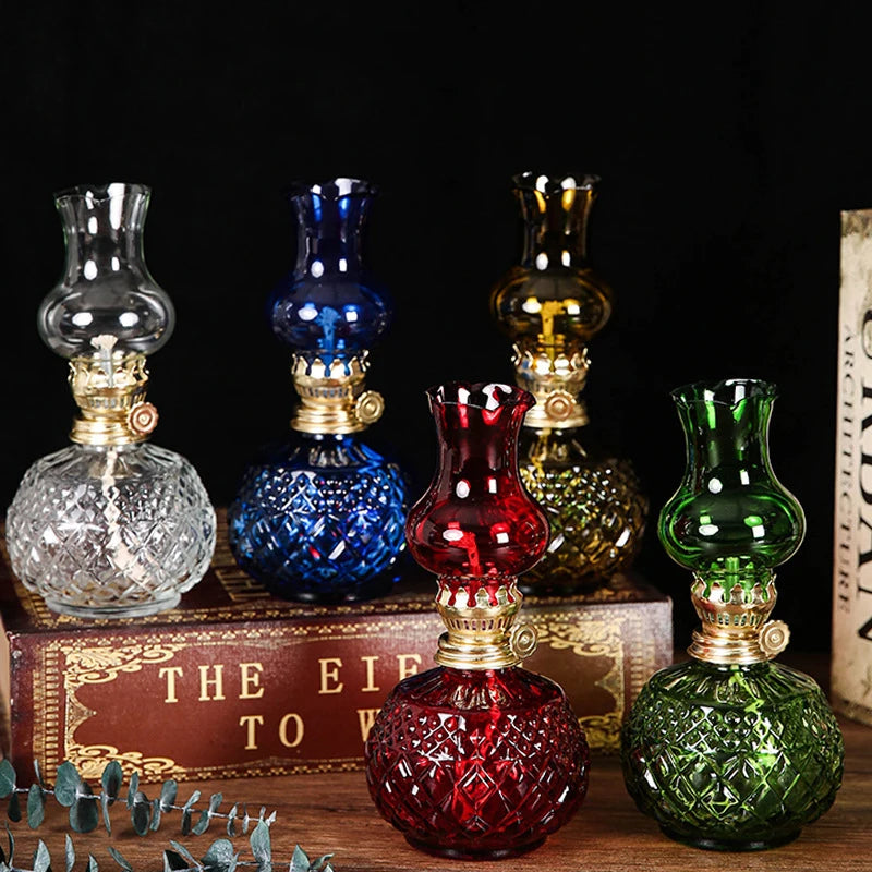 A collection of vintage rustic oil lamps in various colors and glass textures displayed on a wooden surface.