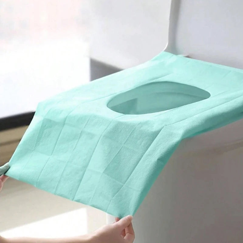 Ein leichter minzgrüner Einweg-Toilettendeckschutz wird auf einer weißen Oberfläche platziert.