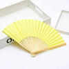 Un éventail pliable jaune vif fait de bambou et de papier, ouvert.