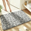 A gray pebble embossed bathroom rug placed on a wooden floor next to a white radiator.