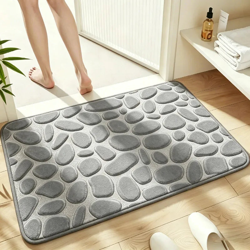 A gray pebble embossed bathroom rug placed on a wooden floor next to a white radiator.