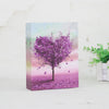 Álbum vertical con un vibrante árbol morado contra un fondo de atardecer rosa.