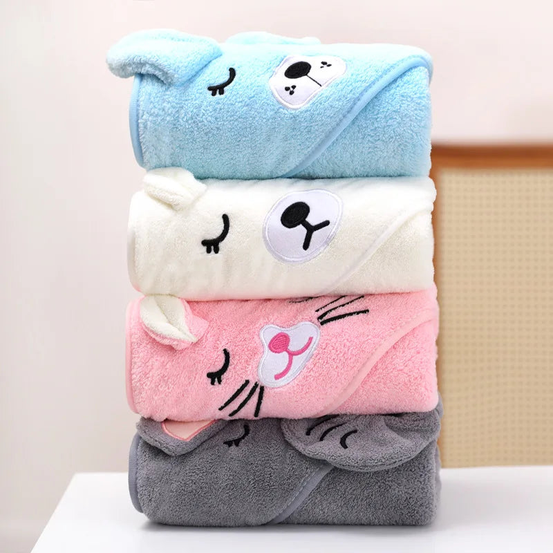 Ein Stapel weicher Baumwoll-Baby-Badehandtücher und Wickel in Hellblau, Creme, Pink und Grau.