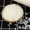 Un cuenco dorado lleno de cuentas de cera de soja blancas y esféricas sobre una superficie a cuadros blanco y negro.
