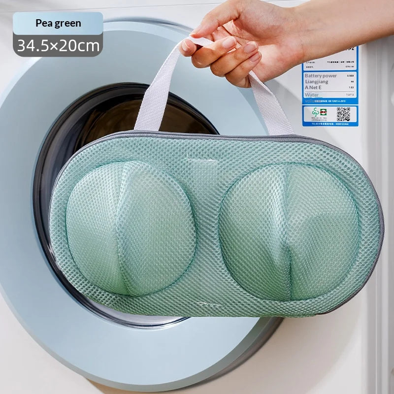 A hand is placing a mesh laundry bag for delicates into a washing machine drum.