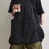 A person wearing a black waterproof outdoor work apron over a black shirt and olive green shorts.