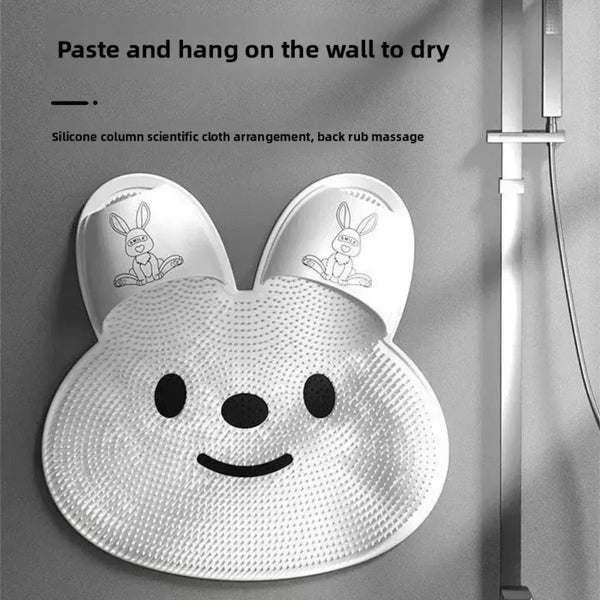 A white silicone mat shaped like a rabbit face is shown hanging on a wall for drying.