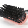 A close-up of a black heavy-duty long-handle floor scrub brush with numerous stiff bristles.