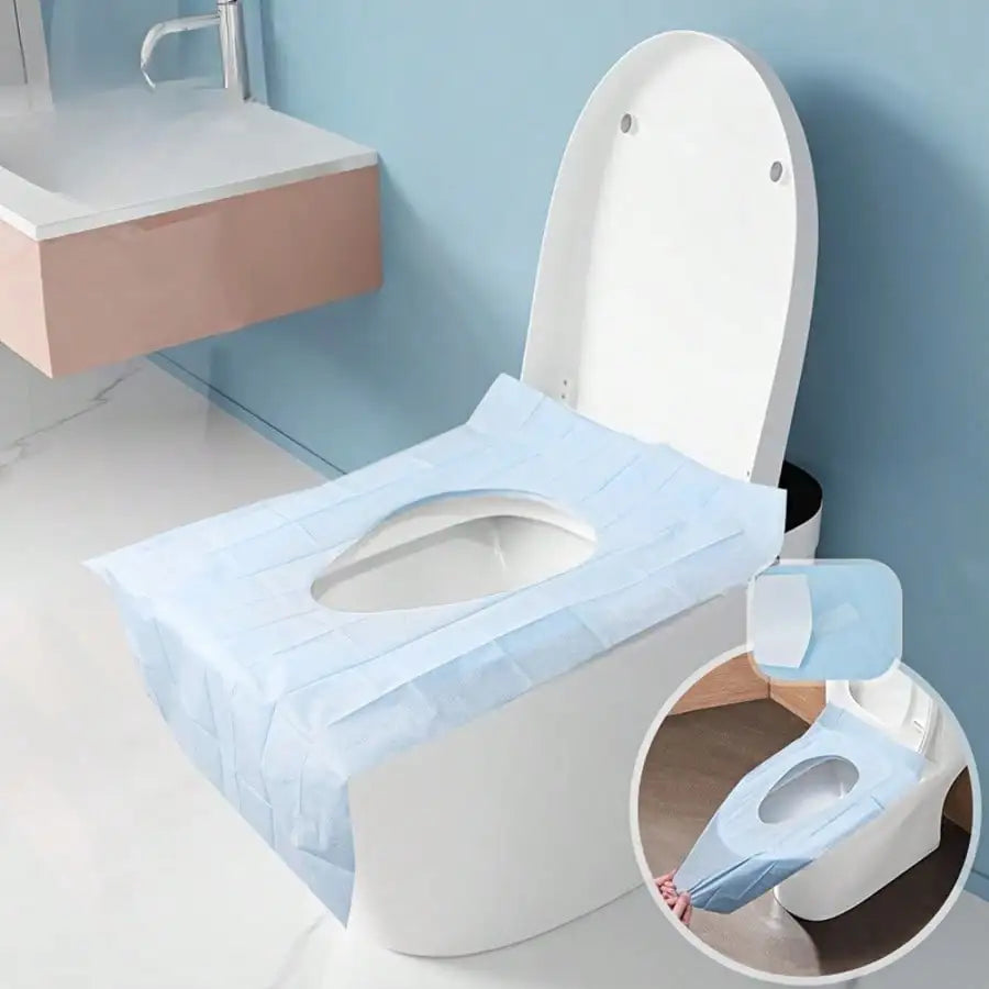 A white toilet with a light blue disposable seat liner placed on the seat.