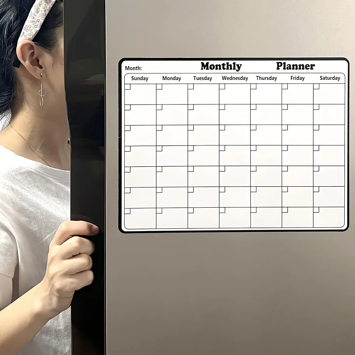 Monatlicher Planer Kalender auf dem Kühlschrank, zeigt Wochentage und Rasterfelder zum Planen.