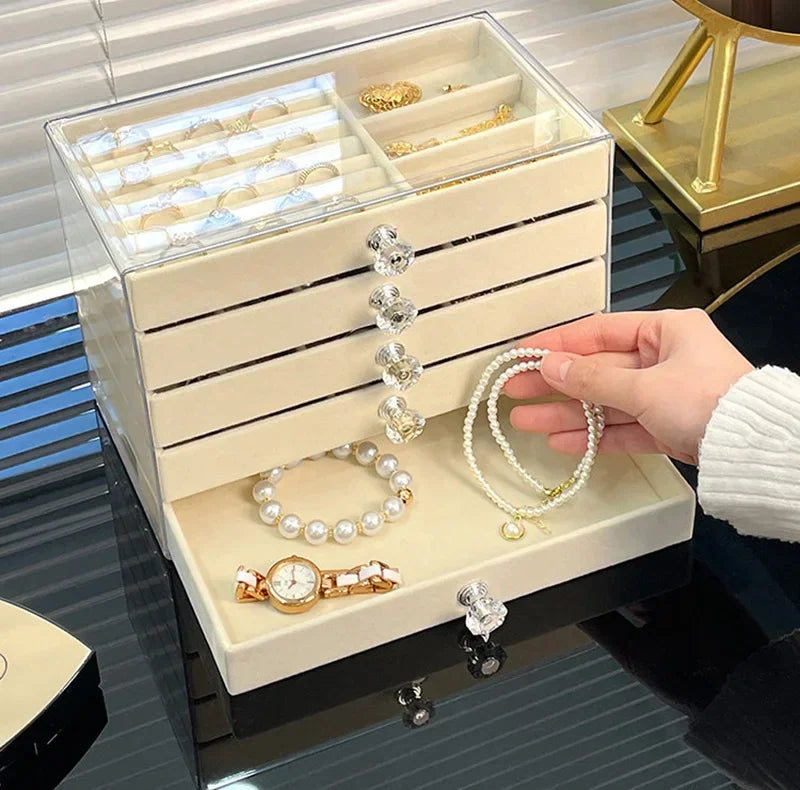 A clear acrylic 5-tier desktop jewelry organizer rack displaying various gold and silver rings and bracelets.