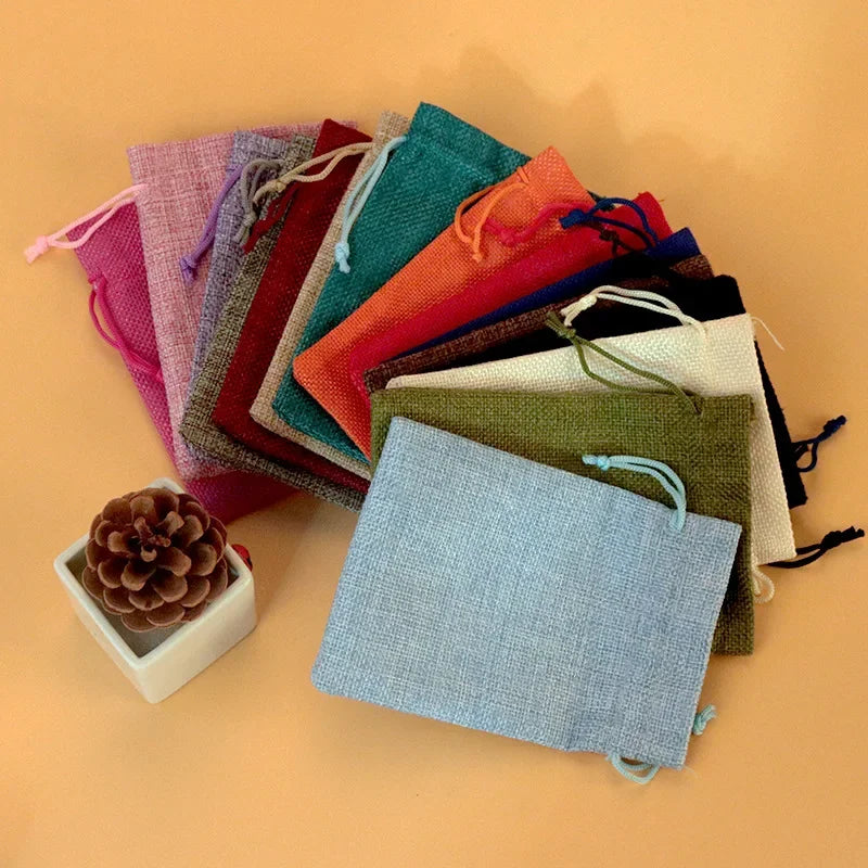 Eine Sammlung handgefertigter Jute- und Leinen-Geschenktüten in verschiedenen Rosa-, Grün-, Orange- und Brauntönen auf einem 